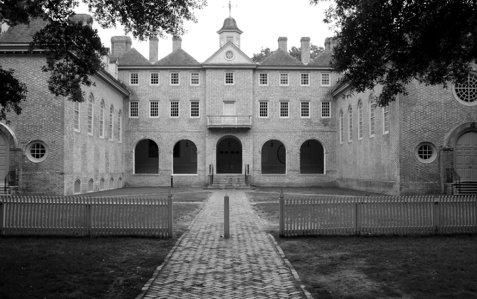 Black and white photo of a historic college with trees in the foreground